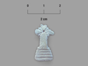 A local ribbed bivalve shell shaped into a cross with a dot and radiating lines thought to represent a monstrance pin or symbol